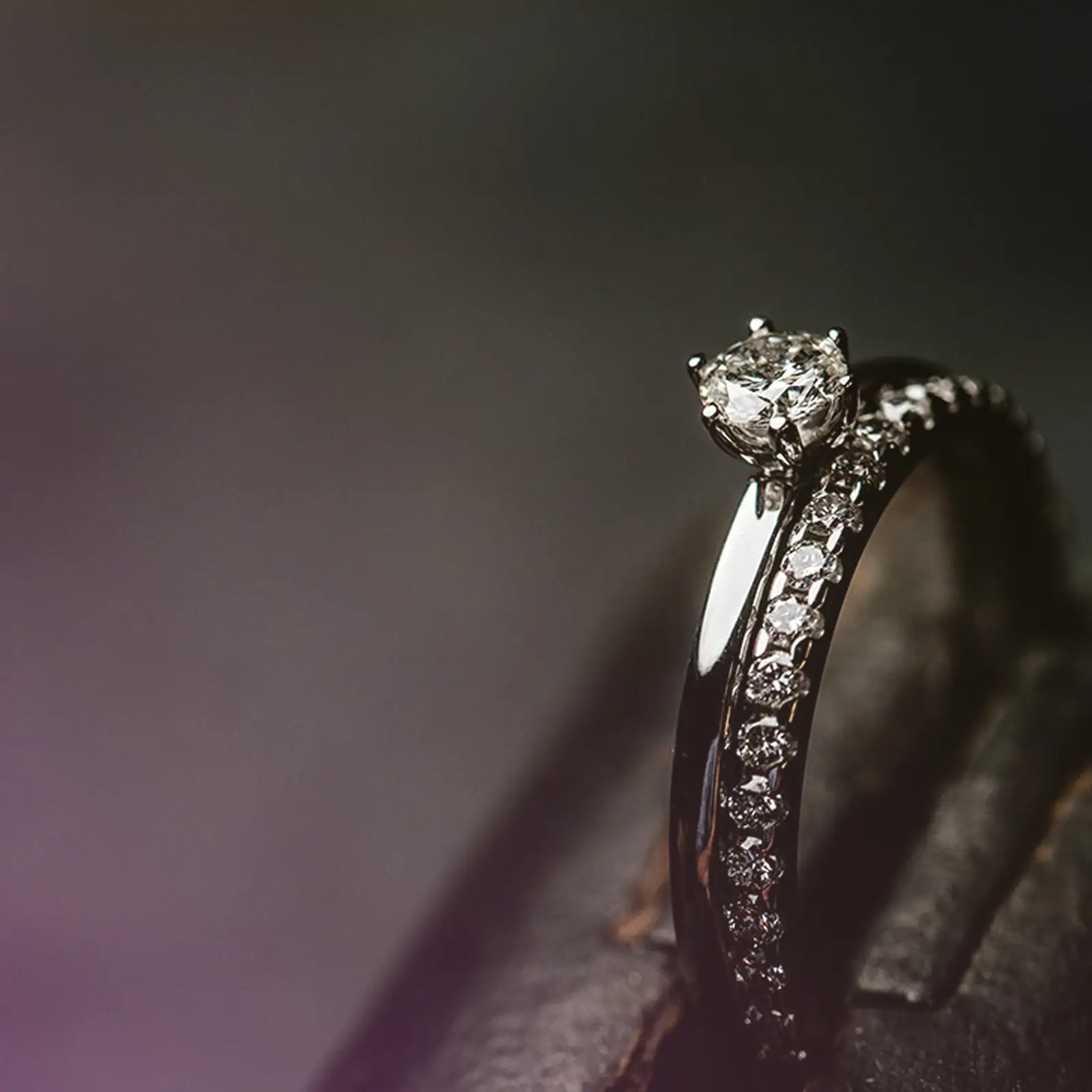 Feiner Verlobungsring aus Weißgold mit Diamantfassung, auf dunklem Untergrund fotografiert